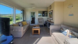 Ein Wohnzimmer mit Sofa, Sessel, Couchtisch und Fernseher.