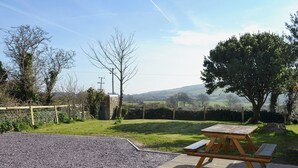 A picnic table in a rural setting with a stone wall, a wooden fence, and a clear sky. - 3 bedroom accommodation in Llaneilian, near Amlwch (Llaneilian, near Amlwch)
