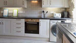 A modern kitchen with white cabinets, a Bosch oven, a washing machine, and a toaster. - 3 bedroom accommodation in Llaneilian, near Amlwch (Llaneilian, near Amlwch)