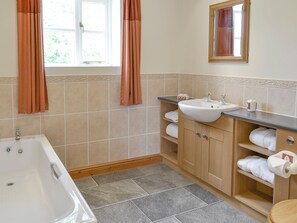 A bathroom with a bathtub, sink, and vanity with towels.