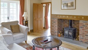 A cozy living room with a fireplace, a sofa, a coffee table, and a door leading to another room. - 1 bedroom accommodation in Cropton, near Pickering (Cropton, near Pickering)