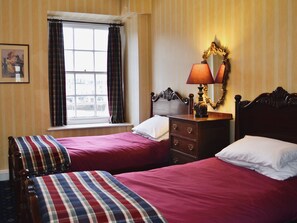 A hotel room with two beds, a dresser, a mirror, and a window with curtains.