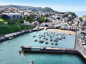 A coastal town with a marina, residential buildings, and a hill in the background.