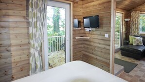 Una stanza in baita di legno con un letto, una televisione e un balcone.