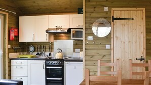 Una cucina funzionale con fornello, forno, microonde, mobili in legno e un'area pranzo con tavolo e sedie.