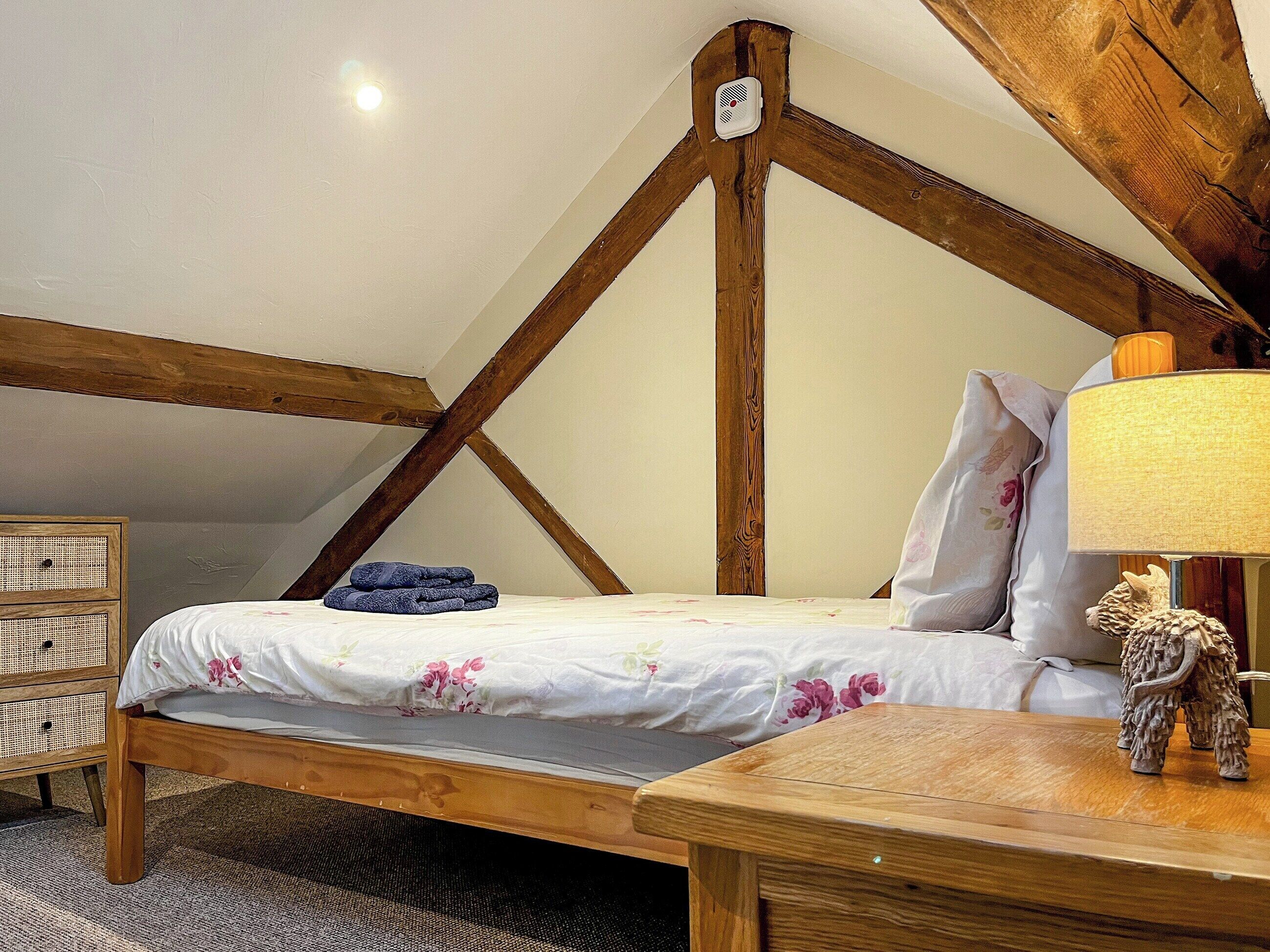 Une chambre à coucher avec un lit en bois, une lampe de chevet, une petite statue et une table de chevet en rotin.