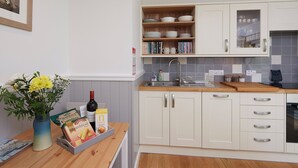 A kitchen with white cabinets, a wooden countertop, a sink, and a vase with flowers on the left. - 1 bedroom accommodation in Newton, near Tain (Newton, near Tain)