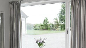 A window with curtains, a vase with flowers, and a view of a green landscape. - 1 bedroom accommodation in Newton, near Tain (Newton, near Tain)
