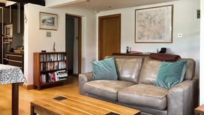 A living room with a leather sofa, a wooden coffee table, a bookshelf, and a framed map on the wall.