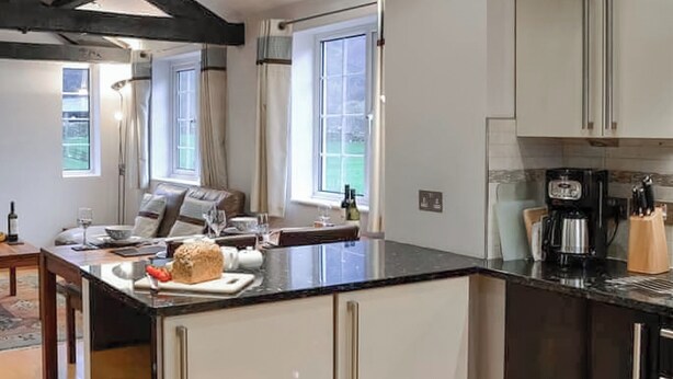 A modern kitchen with a large island, white cabinetry, and a coffee machine.