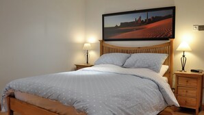 A neatly made bed with a polka dot duvet, wooden headboard, and two bedside tables with lamps.