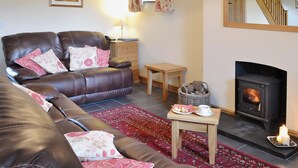 A living room with a sofa, a small table with a cup and pastries, a fireplace, and a staircase.