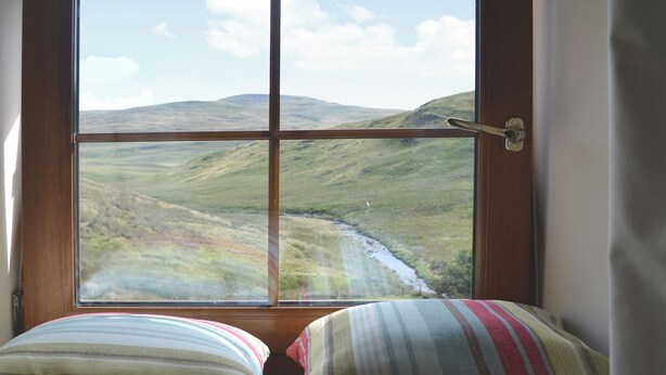 A window with a view of a valley and hills.
