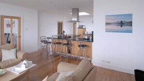 Un salon moderne avec un canapé, un coin repas comprenant une table et des chaises, et une cuisine équipée d’une cuisinière et d’un évier.