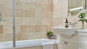 A bathroom with a bathtub, a sink, a mirror, a plant, and a candle. - 3 bedroom accommodation in Pickering (Pickering)