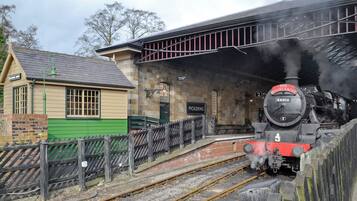 A vintage train station with a steam locomotive, a waiting platform, and a small building labeled 'Pickering.'