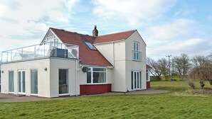 A two-story house with a red-tiled roof, large windows, and a glass conservatory.