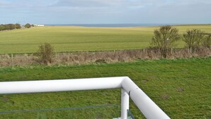 A rural landscape with a field, a fence, and a distant building.