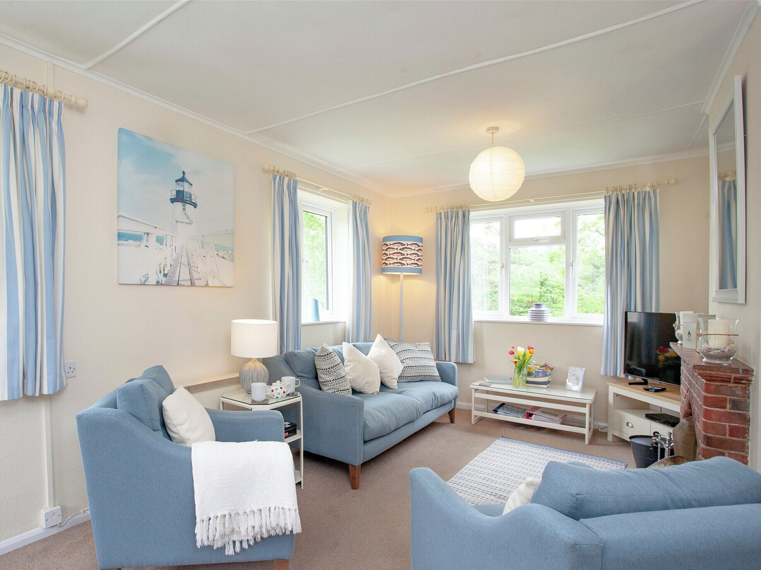 A living room with a blue sofa set, a white coffee table, a TV, and a fireplace.