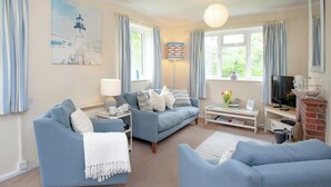 A living room with a blue sofa set, a white coffee table, a TV, and a fireplace.