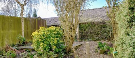 A garden with a stone wall, a wooden fence, and a variety of plants.