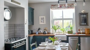 Una cocina con estufa, horno y mesa de comedor lista para una comida.