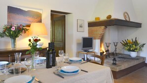 Un comedor con una mesa dispuesta para dos personas, una chimenea y un cuadro en la pared.