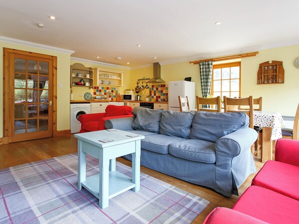A living room with a blue sofa, a white coffee table, and a plaid rug.