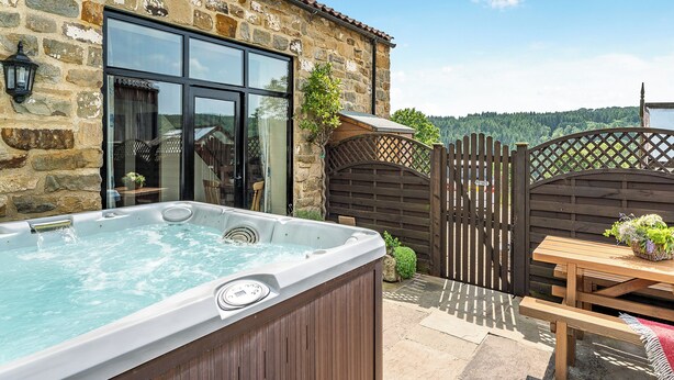 A stone building with a wooden deck, a hot tub, and a picnic table. - 4 bedroom accommodation in Beck Hole, near Goathland (Beck Hole, near Goathland)