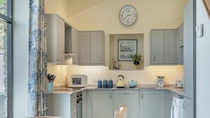 A kitchen with grey cabinets, a microwave, a kettle, and a clock on the wall. - 4 bedroom accommodation in Beck Hole, near Goathland (Beck Hole, near Goathland)