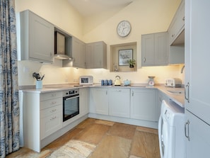 A modern kitchen with grey cabinets, a microwave, a kettle, and a scale.