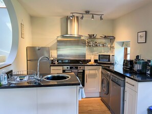 A compact kitchen with a sink, stove, microwave, and washing machine.