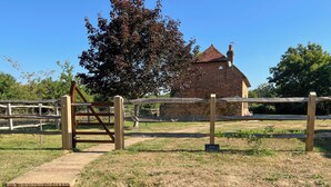 Edifici de maó amb teulada vermella, envoltat per una tanca de fusta i una porta.