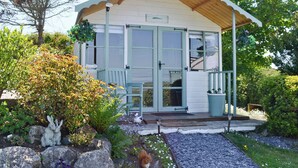 A small, single-story building with a wooden porch and a sign that reads "House to House." - 2 bedroom accommodation in Llanfairynghornwy (Llanfairynghornwy)