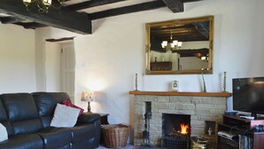 A living room with a fireplace, a television, a sofa, and a coffee table. - Kiln Green Farmhouse (Near Milnthorpe)