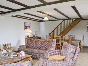 A cozy living room with a wooden staircase, patterned sofa, and a table with books and a tissue box.