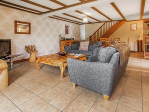 Een woonkamer met een houten salontafel, een grijze bank en een trap.