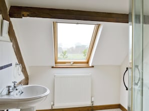 A bathroom with a skylight, a white radiator, and a sink with a faucet. - 3 bedroom accommodation in Catfield (Catfield)