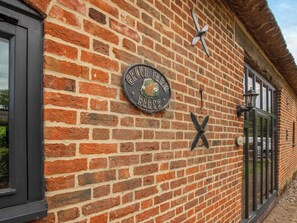 Een bakstenen gebouw met een bord waarop staat 'Grove Farm Barns'.