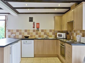 A kitchen with wooden cabinets, a white dishwasher, a microwave, and a sink.