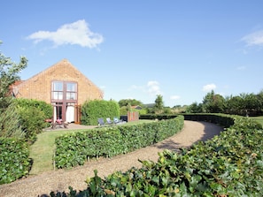 A brick house with a large window, a garden with a gravel path, and a hedge. - 3 bedroom accommodation in Catfield (Catfield)