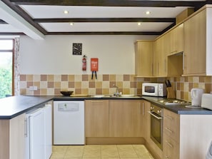 A kitchen with wooden cabinets, a white dishwasher, a microwave, and a sink. - 3 bedroom accommodation in Catfield (Catfield)