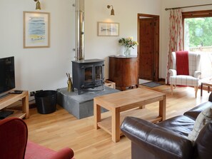 A cozy living room with a fireplace, wooden furniture, and a television.
