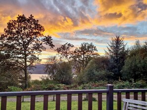 A scenic outdoor area with a wooden deck and a view of trees and hills. - Allt Beag (Little Streams) (Achintraid, near Lochcarron)