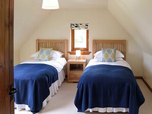 A bedroom with two beds, each with a wooden headboard, a nightstand, and a mirror above the nightstand.