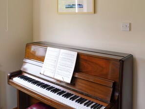 A piano with sheet music on it, a framed picture on the wall, and a light switch. - Allt Beag (Little Streams) (Achintraid, near Lochcarron)