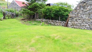 Une zone herbeuse bordée d’un mur de pierres et d’une clôture en bois.
