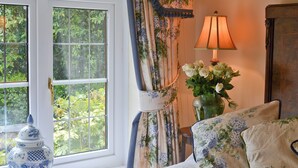 Une pièce comprenant un lit, une lampe, un vase avec des fleurs et un objet décoratif posé sur le rebord de la fenêtre.