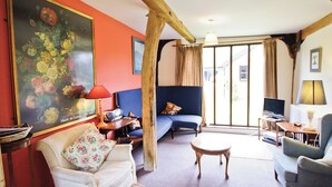 Uma sala de estar com sofá, poltronas, mesa de centro e um quadro na parede.