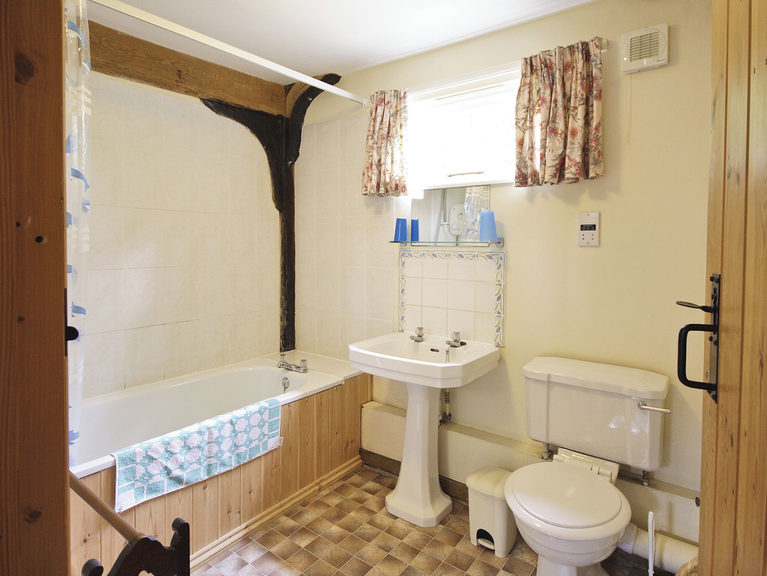 A bathroom with a bathtub, sink, toilet, and wooden paneling.